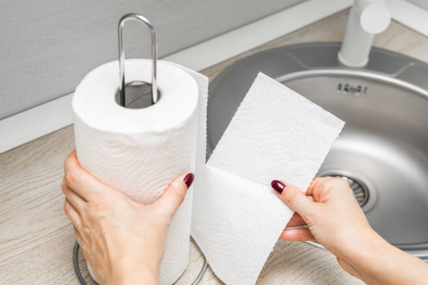 woman's hand ripping off paper towel in kitchen. housewife uses paper towel. roll of paper towel in the kitchen.