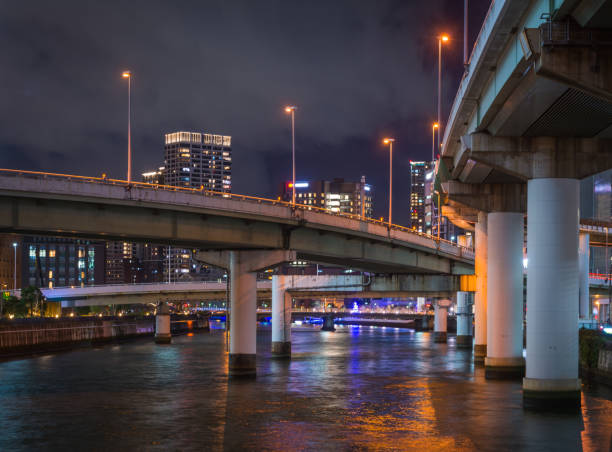 Elevated highways soaring over the tranquil waters of the Kyū-Yodo River reflecting the colourful neon lights of the crowded skyscraper cityscape of downtown Osaka, Japan's vibrant second city.