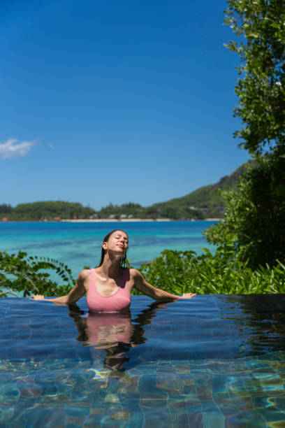 istock Young woman relaxes on edge of swimming pool 2193440468