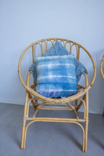 A rattan chair with blue cushions, offering a coastal vibe. Ideal for minimalist interiors. Perfect for home decor and furniture design inspiration.