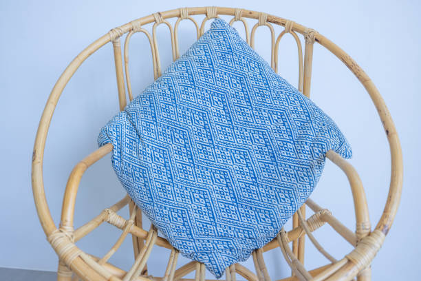 A rattan chair with blue cushions, offering a coastal vibe. Ideal for minimalist interiors. Perfect for home decor and furniture design inspiration.