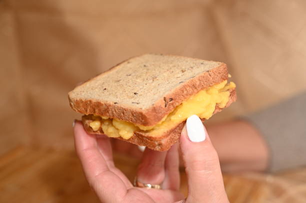 istock Two pieces of toast in hands with melted grilled cheese. 2193442707