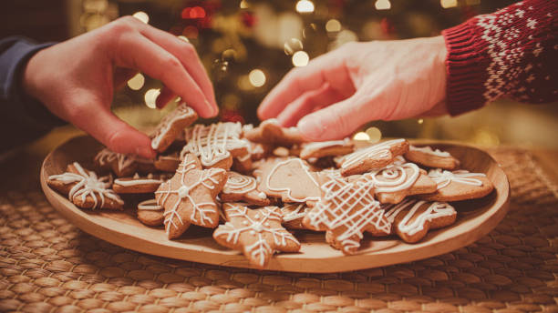 istock Hands take gingerbread from the plate. Christmas tree in the background. 2193447536
