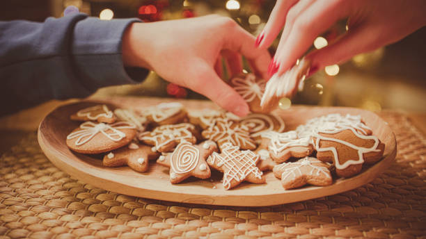 istock Hands take gingerbread from the plate. Christmas tree in the background. 2193447555