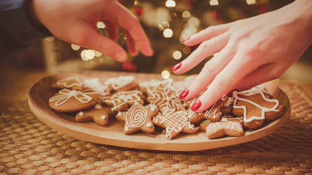 istock Hands take gingerbread from the plate. Christmas tree in the background. 2193447557