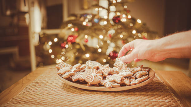 istock Hands take gingerbread from the plate. Christmas tree in the background. 2193447562