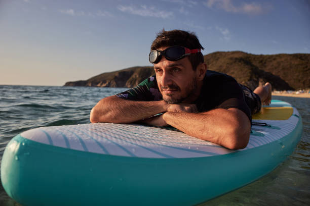 istock Attractive surfer man relaxing on a surfboard during a sunrise 2193450779