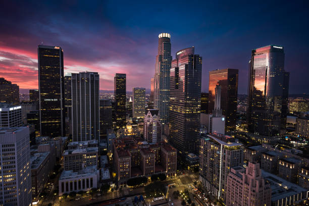 Aerial shot of Downtown Los Angeles at sunset, looking across the Historic Core towards the skyscrapers of the financial district and a colorful pink and purple evening sky.