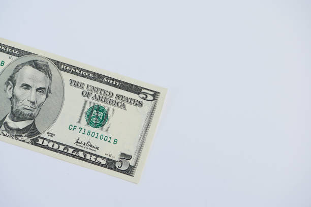 Detailed view of a five dollar banknote laid on a white surface showcasing its features.