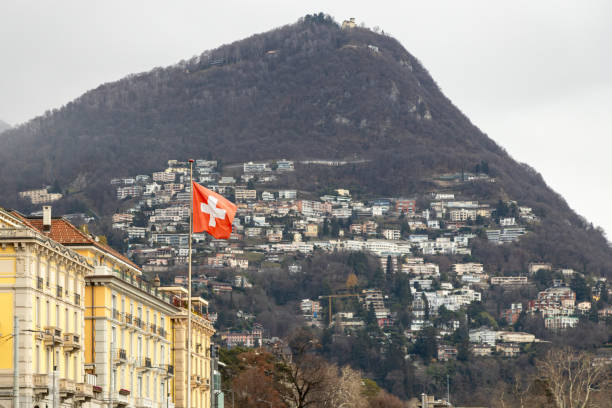 Swiss flag waving, with Monte Bre as the backdrop in Lugano