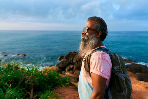istock Senior man explores coastal cliffside, backpacking on scenic ocean hike. Elderly adventurer embraces nature, enjoys fresh sea breeze in twilight years. Multicultural hiker on outdoor travel journey. 2193462211