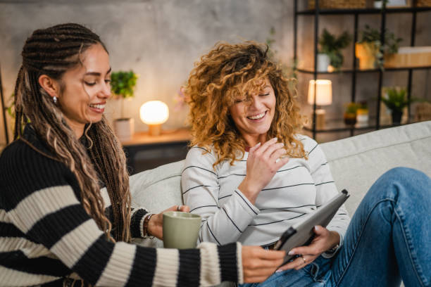 istock cheerful female friends sit on sofa and enjoy while use digital tablet 2193462489