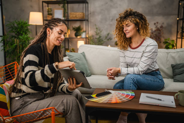 Two women are discussing color samples, suggesting creativity and collaboration in a comfortable, modern interior environment.