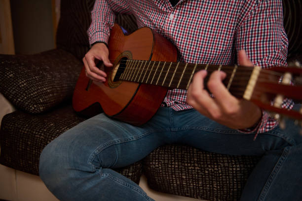 istock Person Playing an Acoustic Guitar While Seated on a Couch 2193465158