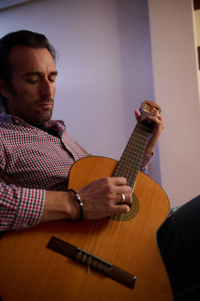 istock Man playing acoustic guitar in a relaxed setting with focus on instrument 2193465175