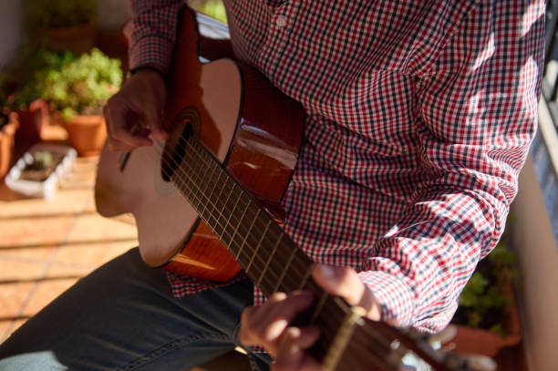 istock Person playing an acoustic guitar in a sunlit outdoor setting 2193465193