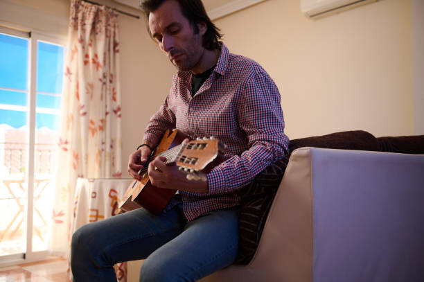 istock Man playing acoustic guitar in a cozy living room setting 2193465200