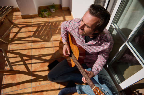 istock Man enjoying guitar playing on the sunny terrace 2193465220