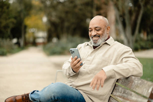 istock Latin American man relaxing in the park and using smartphone 2193470369