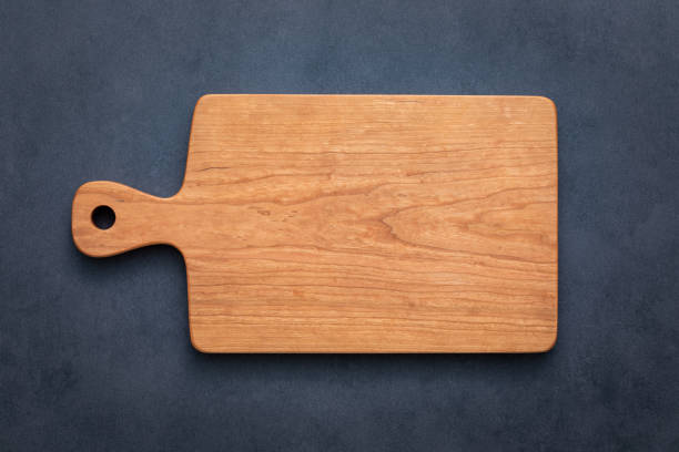istock wooden cutting board isolated. Handmade cherry wood cutting board on cement table top. 2193486064