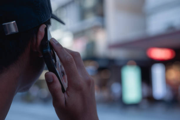 istock Back view of a man using smart mobile phone calling or talking on the phone with bokeh street light 2193492518