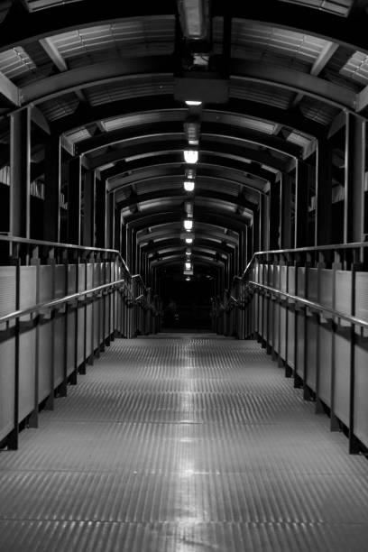 istock Pedestrian bridge with a metallic walkway and arched overhead structure at night 2193495156