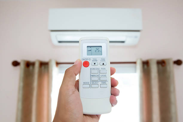 istock Hand using remote control for air conditioner mounted on wall in bedroom. 2193495506