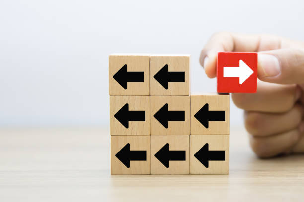 istock Hand chooses arrow icon point to the opposite side on wooden toy block stack for adaptation challenge change transformation business plan and choice the way forward goal to growth 2193495519