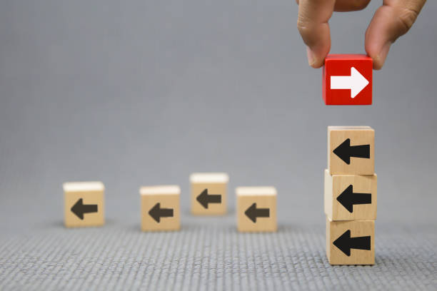istock Hand chooses arrow icon point to the opposite side on wooden toy block stack for adaptation challenge change transformation business plan and choice the way forward goal to growth 2193495520