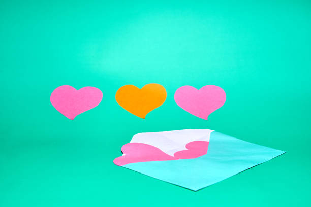 An open light blue envelope with pink hearts peeking out, flanked by two pink hearts and one orange heart on a teal background