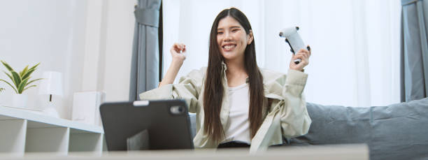 istock Happy young asian woman at home, play mobile video game app on digital tablet using console controller. Internet application technology, portable computer gaming, modern gadget lifestyle. Copy space 2193497654