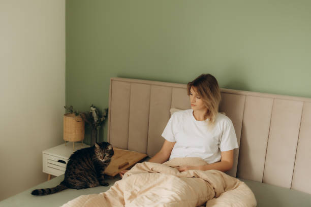 istock Young woman with cute cat sleeping in bed 2193502068