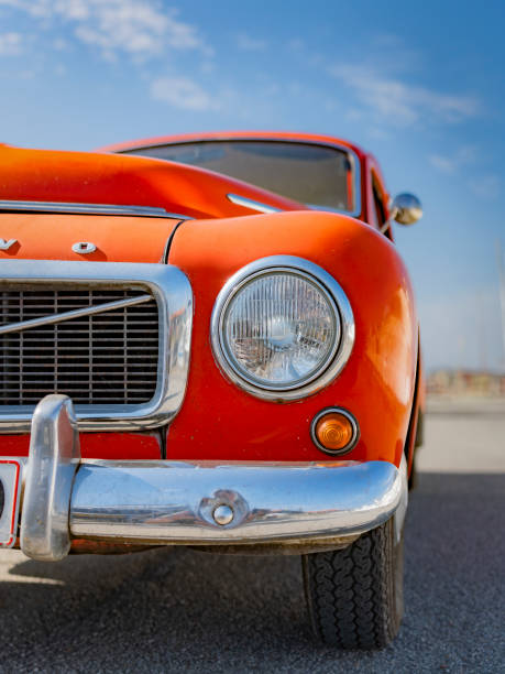Partial view of a red Volvo PV 544 from the front, blue sky in the background, vertical