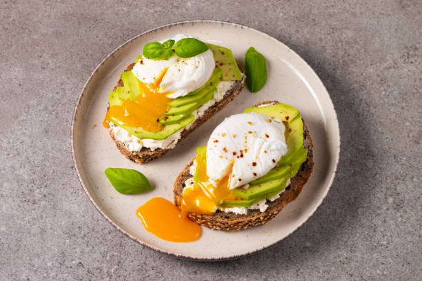 istock Toast with avocado, soft cream cheese, rye bread and poached Egg. Wholemeal open sandwich for healthy breakfast concept 2193509683
