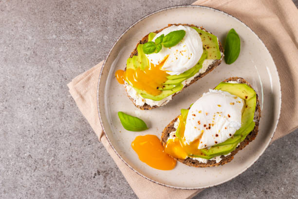 Toast with avocado, soft cream cheese, rye bread and poached Egg. Wholemeal open sandwich for healthy breakfast concept