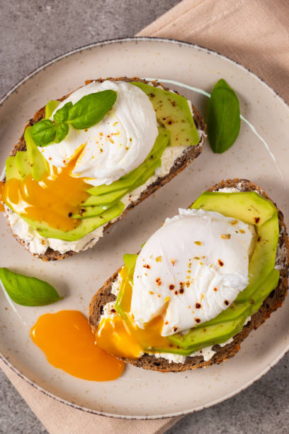 istock Toast with avocado, soft cream cheese, rye bread and poached Egg. Wholemeal open sandwich for healthy breakfast concept 2193509726