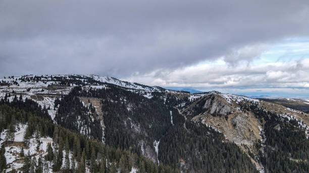 istock Drone view of a melting snow-covered mountain with distant sunlit peaks and a clear blue sky dotted with clouds, showcasing a beautiful alpine landscape. 2193510130