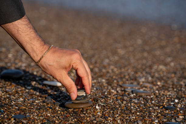 istock A man stacking stones on the beach with sea view in the background 2193511120
