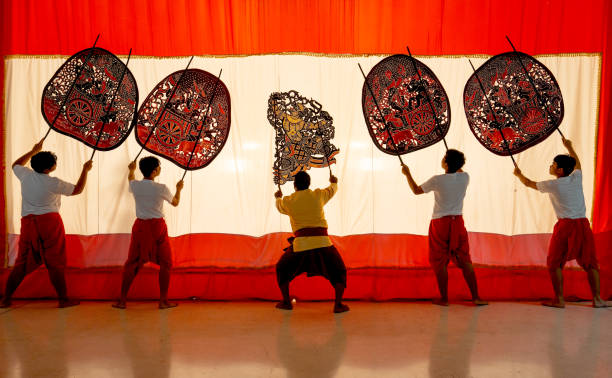 istock Five player men stand with perform grand shadow play in front of white screen with action as performance of the show. 2193512028