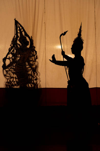 istock Vertical image silhouette of Khon or Mask dance player stand with performance action in front of grand shadow play in the background with white screen. 2193512384