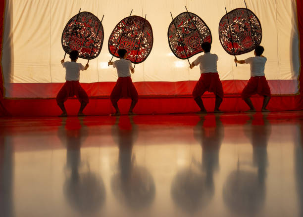 istock Four player men stand with perform grand shadow play in front of white screen with reflection on the floor. 2193513378