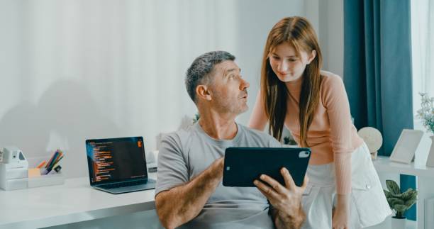 istock Senior father and daughter smile as they use digital tablet together in cozy home, emphasizing family bonding and technology use. Lifestyle family. 2193513521