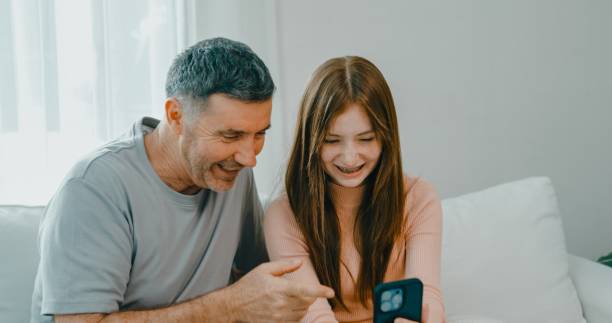 istock Mature father and daughter share a joyful moment as they make a video call using a smartphone at home. Family bonding and the use of technology. 2193513533