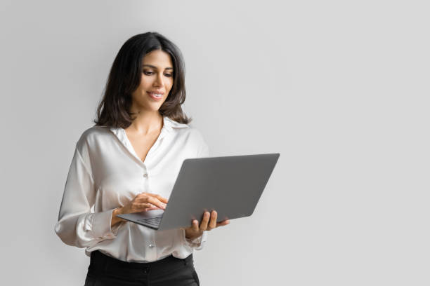 istock Focused young middle eastern Israel businesswoman using laptop pc online application for work isolated on white wall. Indian or arabic woman in business suit holding computer, doing data base research 2193514288