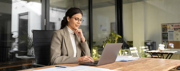 istock Young businesswoman professional employee using pc doing online banking analysing at workplace. Latin hispanic middle age business woman working on laptop computer in modern office. Banner, copy space 2193514313