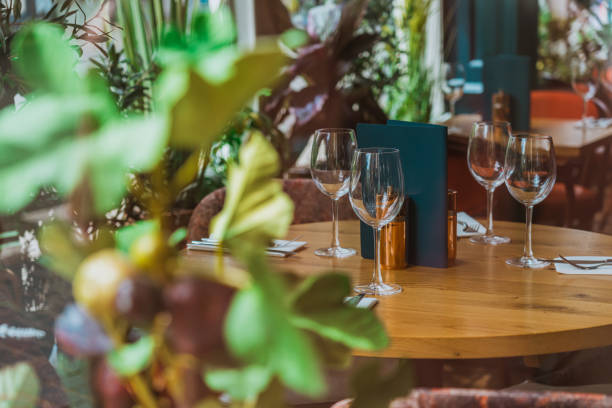 istock Empty wine glasses resting on wooden restaurant table surrounded by lush greenery 2193515697