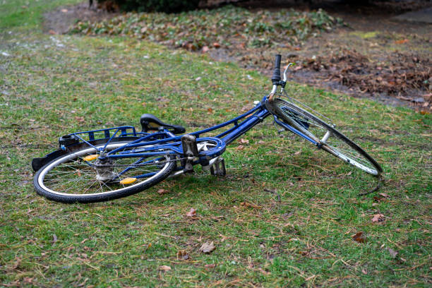 View of a blue broken bicycle lying on green grass.