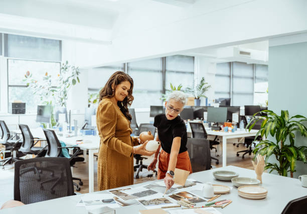 istock Two women collaborating at a brightly lit office desk reviewing documents and discussing creative ideas together 2193516628
