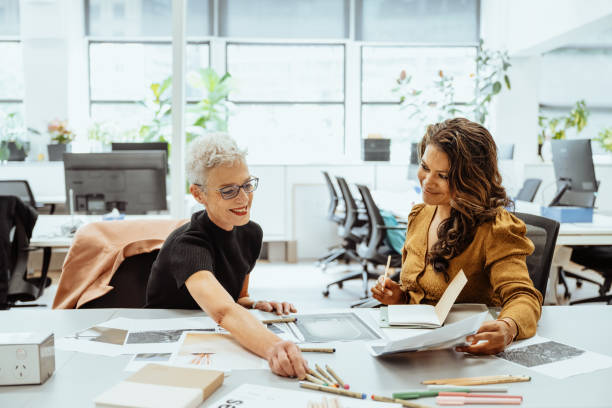 istock Two mature entrepreneurs collaborating at a brightly lit office desk reviewing documents and discussing creative ideas together 2193516646
