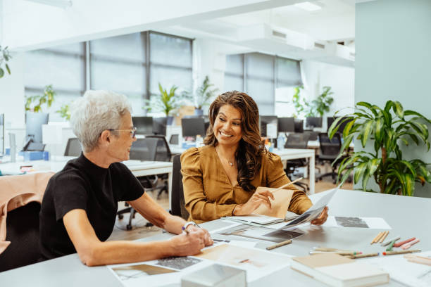istock Two mature women collaborating at a brightly lit office desk reviewing documents and discussing creative ideas together 2193516649